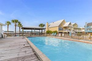 a swimming pool with a wooden deck next to some houses at Lagoon Landing #302 in Gulf Shores