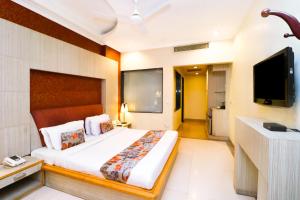 a bedroom with a large bed and a flat screen tv at Hotel Rajshree & Spa in Chandīgarh