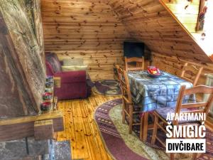 una sala da pranzo in una baita di tronchi con tavolo e sedie di Apartmani Smigic Divcibare a Divčibare