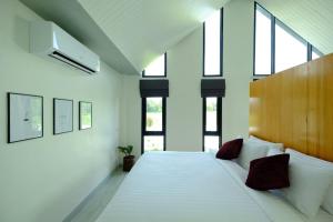 - une chambre avec un grand lit blanc et des fenêtres dans l'établissement Baan Ga-Cha, à Chiang Rai