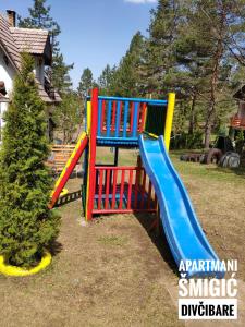 a playground with a colorful slide in a yard at Apartmani Smigic Divcibare in Divčibare