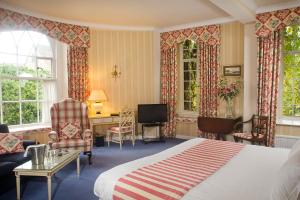 een slaapkamer met een bed, een bureau en ramen bij Castle Hotel in Taunton