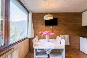 a dining room with a table with a vase of flowers at Appartamento Volpi in Mezzana