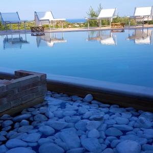 una piscina de agua azul con mesas y sillas en Cristina & Margot, en Noto