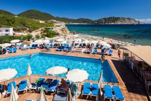 
a beach filled with lots of chairs and umbrellas at Invisa Hotel Club Cala Blanca in Es Figueral Beach
