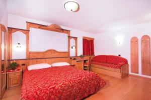 a bedroom with a large red bed and a window at Hotel il Caminetto Sport in Canazei