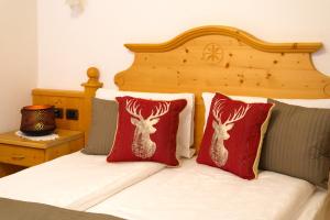 - un lit avec 2 oreillers rouges et des têtes de cerf dans l'établissement Hotel il Caminetto Sport, à Canazei