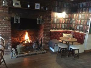 a living room with a fireplace and a table and a fire place at The Bell Inn, Rickinghall in Rickinghall
