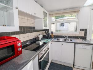 a kitchen with a red microwave and a sink at Driftwood in Wadebridge