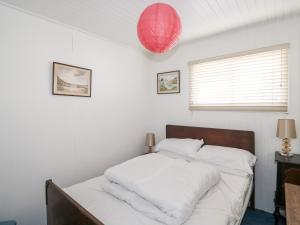 a bedroom with a bed with white sheets and a red lantern at Driftwood in Wadebridge