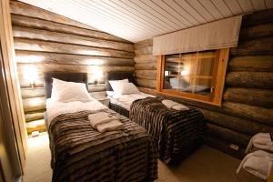 Cette chambre comprend 2 lits et une fenêtre. dans l'établissement Kelokolo, Ivalo, à Ivalo
