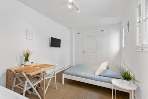 Cette chambre blanche comprend un lit et une table. dans l'établissement LGC Habitat - Studios Hyper Centre, à Montpellier