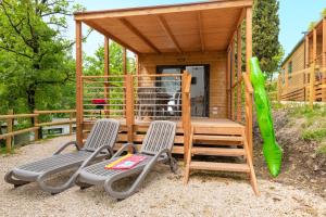a tiny house with two chairs and a playground at Fornella Camping & Wellness family resort in San Felice del Benaco