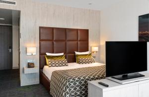 een slaapkamer met een groot bed en een flatscreen-tv bij Van der Valk Hotel Oostzaan - Amsterdam in Oostzaan