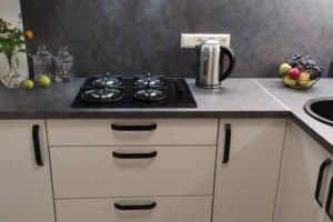 a kitchen counter with a stove and a sink at Butas miesto centre/ Apartment in the city center in Šiauliai