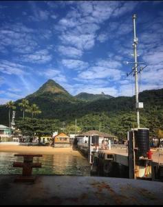 un barco atracado en una playa con montañas de fondo en Vivenda Cravo&Canela, en Abraão