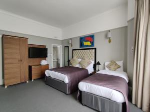 um quarto de hotel com duas camas e uma televisão em Blue Bells Hotel em Londres