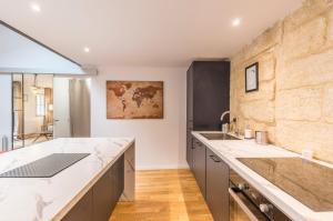 une cuisine avec des comptoirs blancs et un mur en pierre dans l'établissement La Parenthèse Roucher Montpellier - Duplex Climatisé T2 Cœur écusson, à Montpellier
