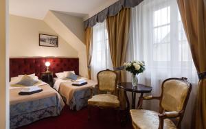 ein Hotelzimmer mit 2 Betten, einem Tisch und Stühlen in der Unterkunft Hotel Stary Zdrój in Świeradów-Zdrój