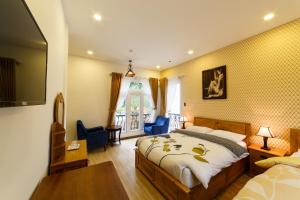 Schlafzimmer mit einem Bett, einem Schreibtisch und einem TV in der Unterkunft Joy Villa in Da Lat