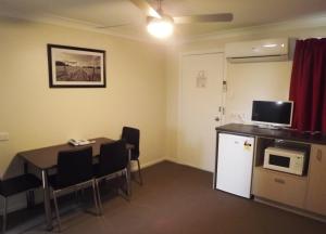 a room with a table and a kitchen with a microwave at High Street Motor Inn in Stanthorpe