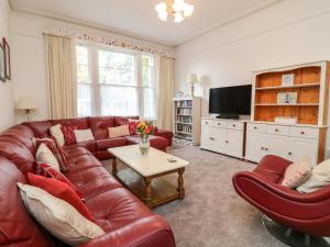 una sala de estar con un sofá de cuero rojo y sillas en Babbacombe Hall, en Torquay