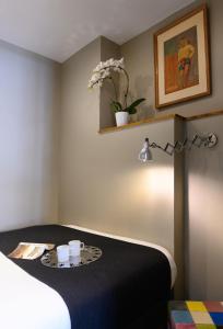 パリにあるスイート＆ホテル ヘルツィア モンパルナスのテーブルにカップ2つが付いたベッド1台が備わる客室です。