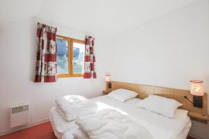 Cama blanca en habitación con ventana en Residence Les Chalets d'Aurouze - maeva Home, en La Joue du Loup