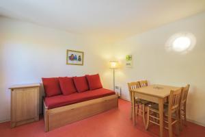 - un salon avec un canapé rouge et une table dans l'établissement Residence Les Chalets d'Aurouze - maeva Home, à La Joue du Loup