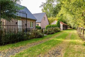 una entrada que conduce a una casa con una valla en De Smokkelaar & Het Schuurtje en Maldegem
