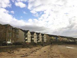a row of buildings on a sandy beach with a row at Beach House No1 With Amazing Sea Views And Direct Beach Access in Fairlie