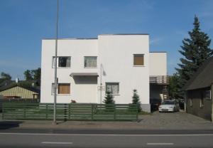 Uma casa branca com uma cerca verde à frente. em Anette House em Pärnu