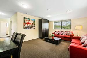 a living room with a red couch and a table at Quality Suites Amore in Christchurch