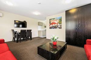 - un salon avec un canapé rouge et une table dans l'établissement Quality Suites Amore, à Christchurch