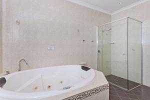 a white bath tub sitting next to a white sink at Quality Hotel Bayswater in Perth