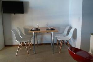- une table avec des chaises blanches et des verres à vin dans l'établissement Amplio, céntrico, luminoso, à Rosario