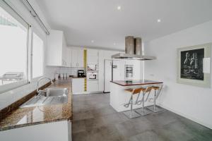 a kitchen with white walls and a counter with stools at Villa Carlota Costa Adeje in Adeje