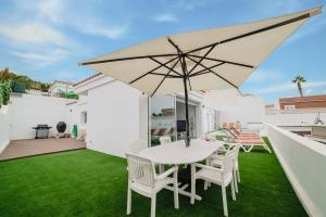 a patio with a white table and chairs and an umbrella at Villa Carlota Costa Adeje in Adeje