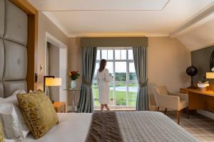a woman standing in front of a window in a hotel room at Carden Park Hotel, Golf Resort and Spa in Tilston