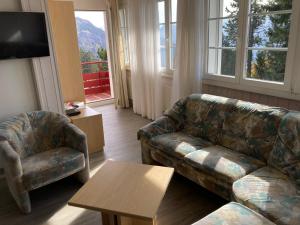 ein Wohnzimmer mit einem Sofa, einem Stuhl und einem Tisch in der Unterkunft Chalet Bergli in Rigi Kaltbad