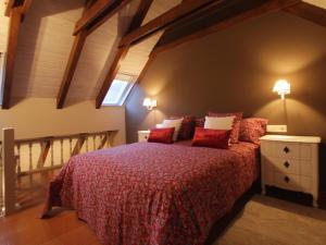 um quarto com uma cama com lençóis vermelhos e uma janela em Hotel Ostau d'Òc em Vielha
