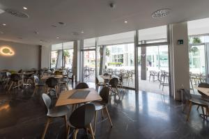 un ristorante con tavoli, sedie e finestre di Hesperia Hotel & Residence a Lido di Jesolo