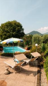 - deux chaises et un parasol à côté de la piscine dans l'établissement Agriturismo Renzano garden apartments, à Salò