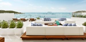 a patio with white couches and a view of the ocean at Nobu Hotel Ibiza Bay in Talamanca