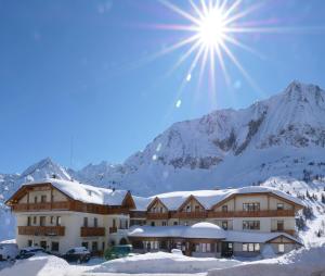 ein Gebäude im Schnee mit der Sonne am Himmel in der Unterkunft Hotel Gardenia in Passo del Tonale