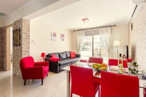 uma sala de estar com cadeiras vermelhas e uma mesa em Nissi 3 Pool Access Garden Apartment em Agia Napa