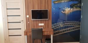 a room with a tv and a painting of a bridge at Metropolis Apartamenty Centrum in Kalisz