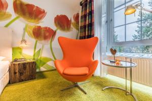 einen orangenen Stuhl in einem Zimmer mit Fenster in der Unterkunft Wellings Parkhotel in Kamp-Lintfort