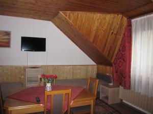 a dining room with a table and a tv at Tóth Vendégház in Parád