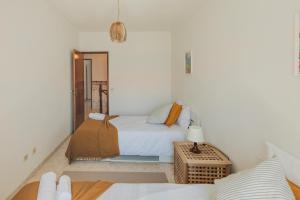 a white bedroom with a bed and a table at Zambujeira do Mar 4-Bed House Perfect for Families & Friends in Zambujeira do Mar